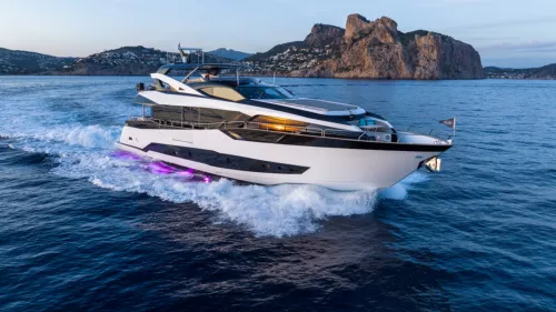 A luxurious yacht sails off an island at sunset.