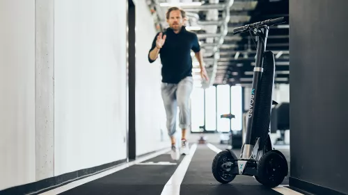 Mann sprintet in einem sehr modernen Büro den Gang entlang, das XBoard steht am Rand.